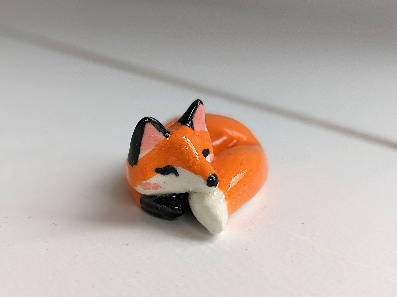 Figurine miniature de renard roux dormant dans une tasse de thé
