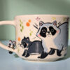 adorable hand sculpted mug with raccoon family