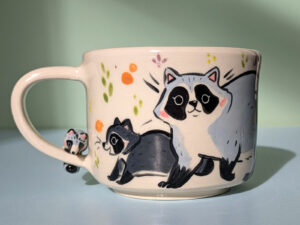 adorable hand sculpted mug with raccoon family