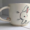 adorable white mug with bunnies and a sculpted handle with a tiny bun