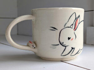 adorable white mug with bunnies and a sculpted handle with a tiny bun