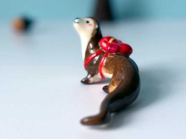 adorable porcelain otter figurine with a backpack