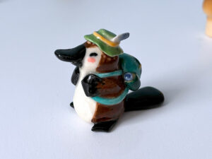 adorable platypus figurine with a backpack and feathered hat