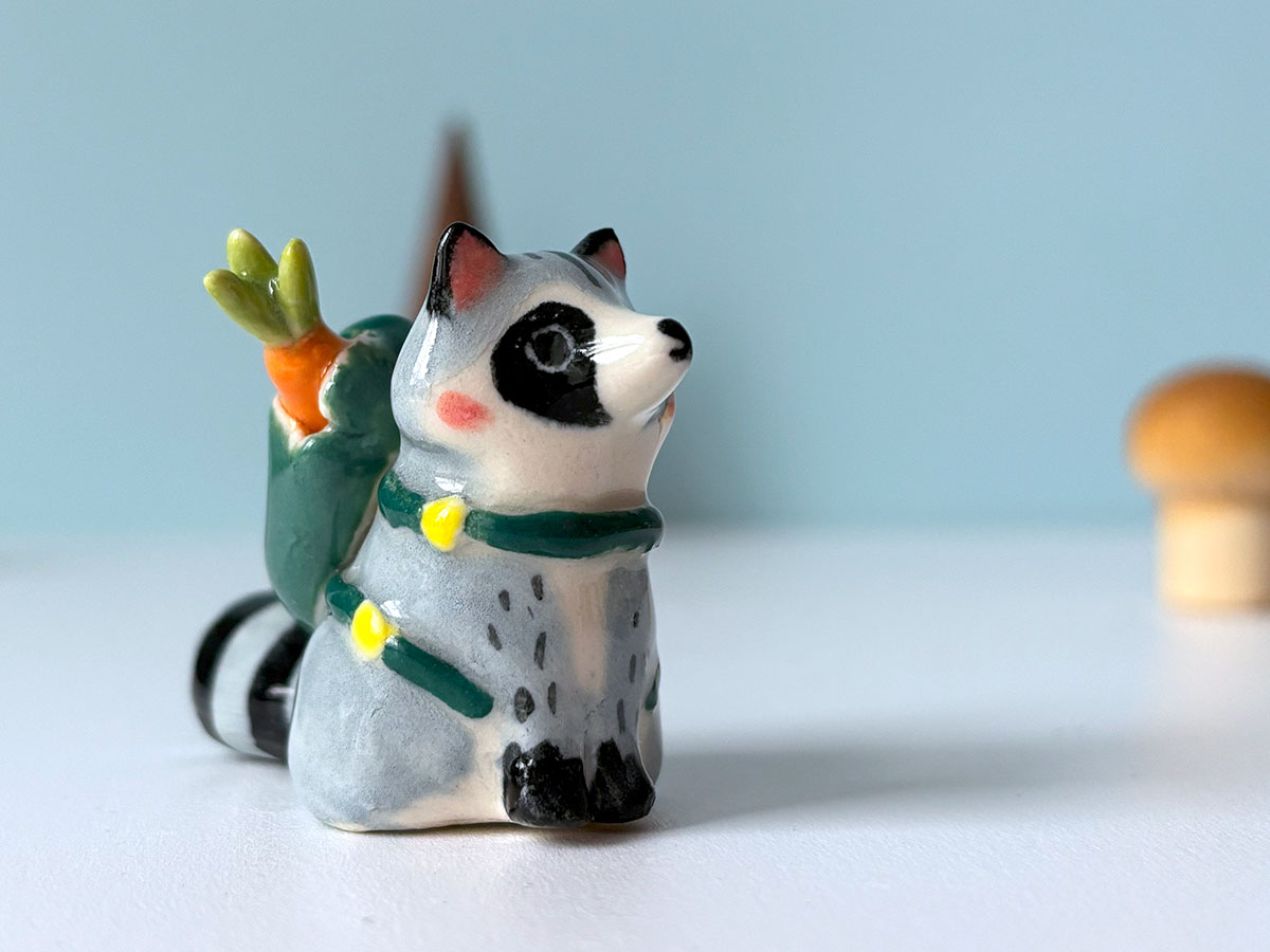 handmade figurine from Canada, porcelain raccoon with a backpack made by kness