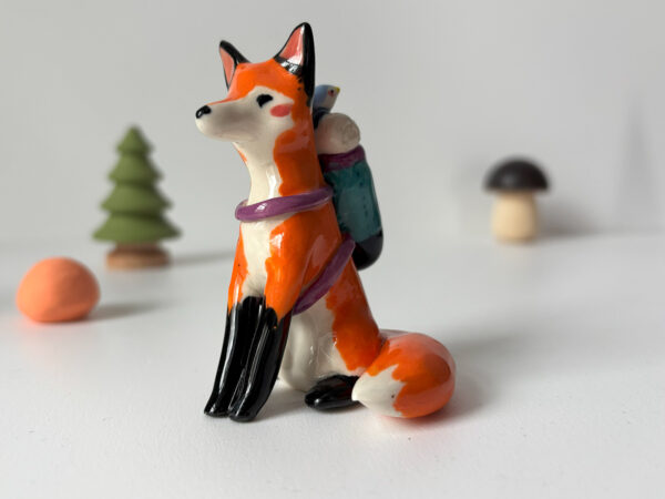 adorable figurine of a fox in a backpack with a passenger